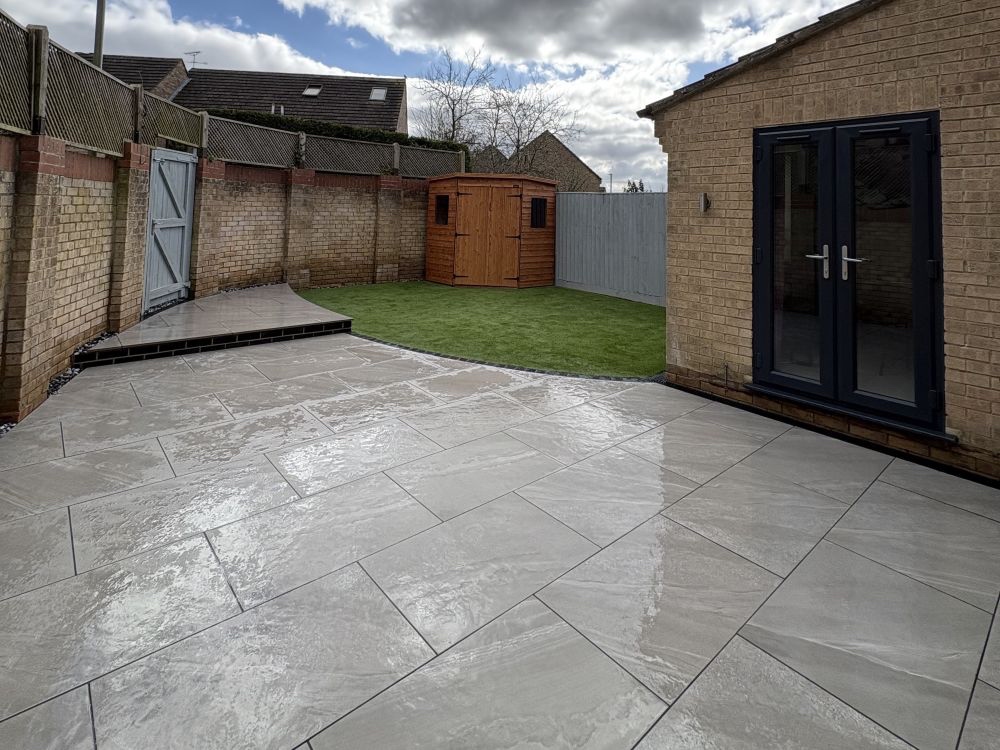 Newly laid porcelain patio with artificial lawn corner and garden shed
