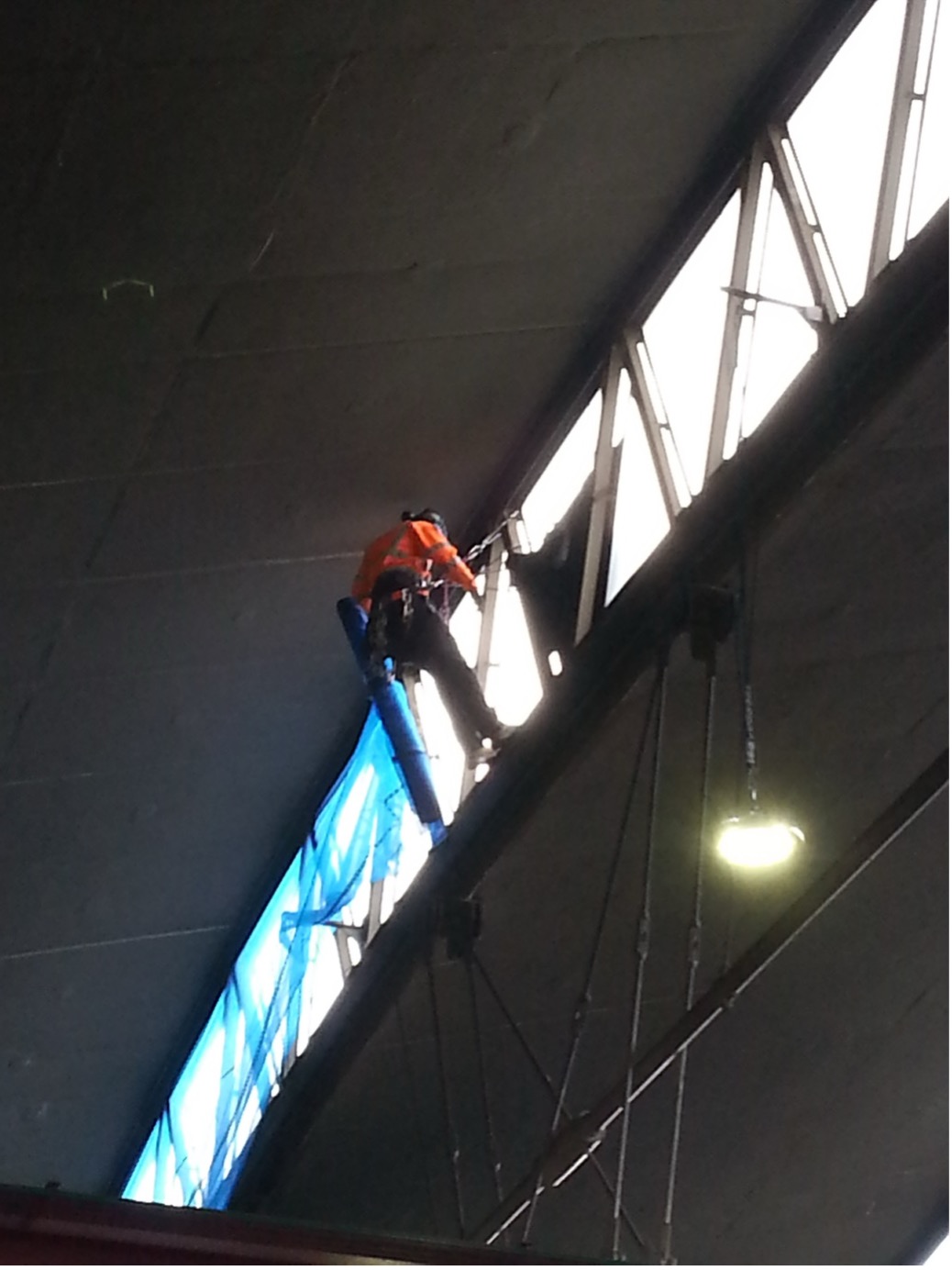 Rope access specialist carrying out internal glazing repairs at height